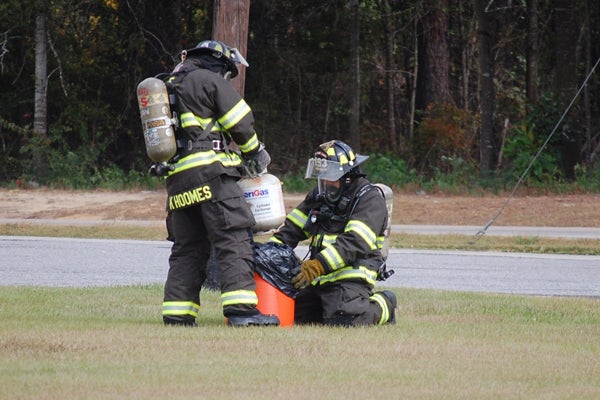 Brewton firefighters load a potentially hazardous tank into a cooler to dispose of it.