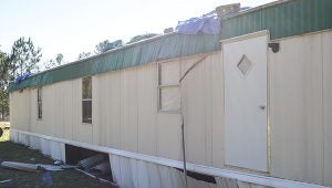 Corey Williams | The Brewton Standard A back view of Banton's home. The rough is covered with tarps and damage is down at the foundation level of the trailer home.